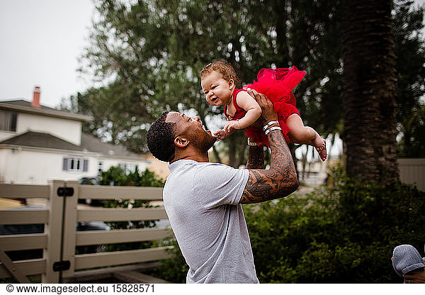 African American Dad Holding Biracial Daughter and Smiling