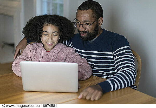 African-American father and bi-racial tween daughter on laptop