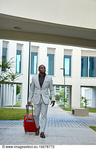 African-American in a white suit and a red suitcase.