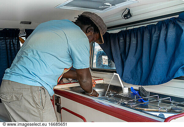African American man cooking in a camper van