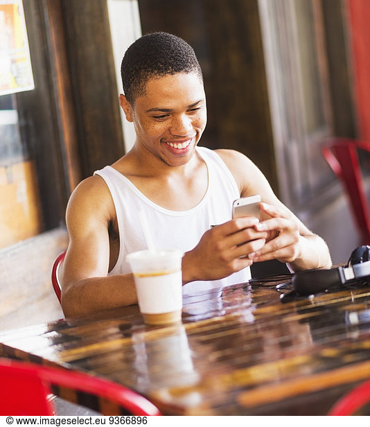 African American man using cell phone at cafe