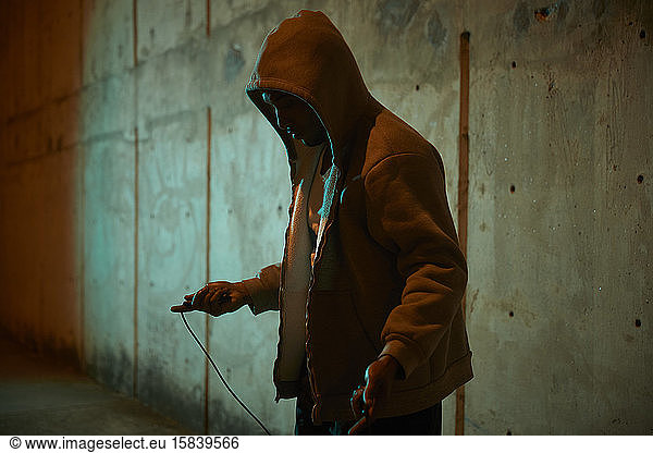 African-American man wearing hoodie preparing to jump rope at night