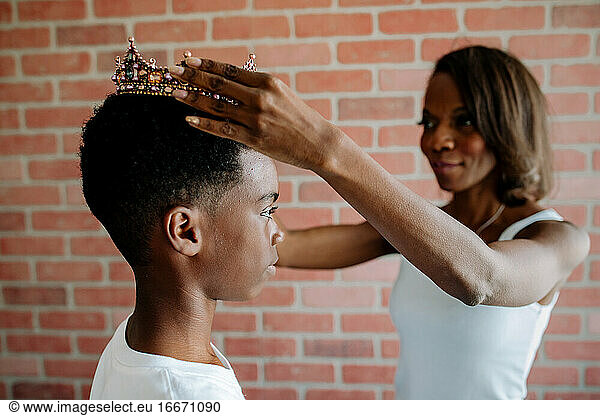 African American mom places crown on serious preteen son