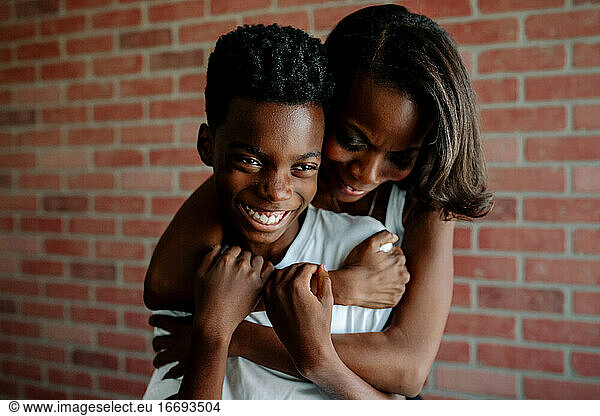 African American mother wrapping arms around happy preteen son