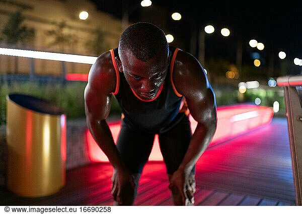 African American runner resting on night street