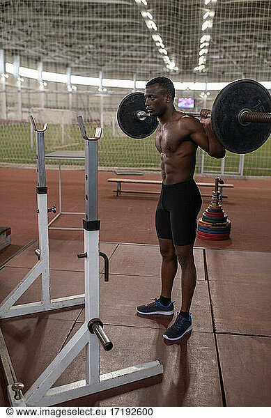 African American sportsman exercising with barbell