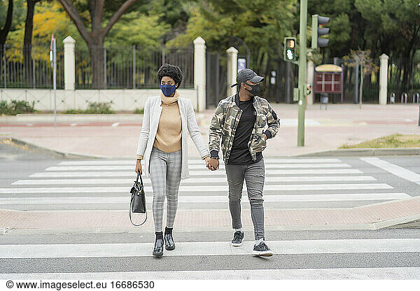 African wedding couple crossing the road hand in hand