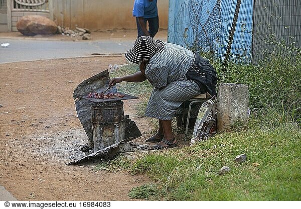 Afrikanische Frau bei der Zubereitung des Shisenyama -Straßengrills im Township Soweto  Südafrika