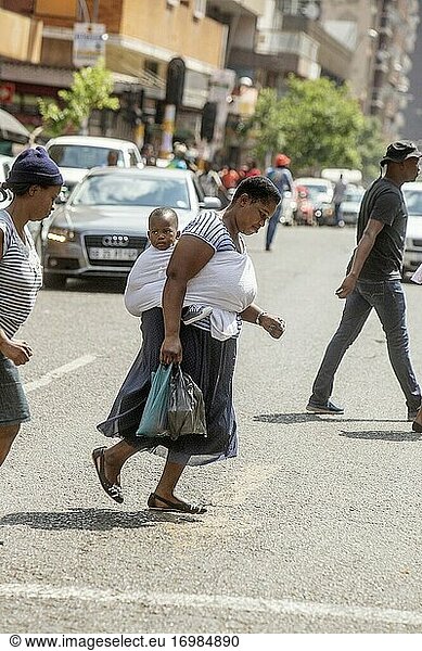 Afrikanische Frau geht in Hillbrow mit Baby auf dem Rücken spazieren  Johannesburg  Südafrika