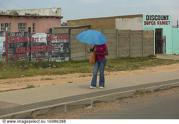Afrikanische Frau geht mit Regenschirm in Soweto Township  Johannesburg  Südafrika