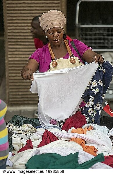 Afrikanische Frau inspiziert Kleidung auf einem Straßenmarkt in Johannesburg  Südafrika
