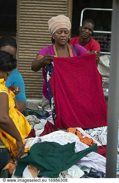 Afrikanische Frau inspiziert Kleidung auf einem Straßenmarkt in Johannesburg  Südafrika