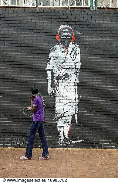 Afrikanischer erwachsener Mann  der an einem Graffiti im Stadtteil Maboneng  Johannesburg  Südafrika  vorbeigeht