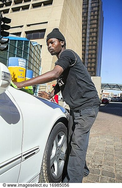 Afrikanischer junger Mann wäscht ein Auto im Stadtzentrum von Johannesburg  Südafrika
