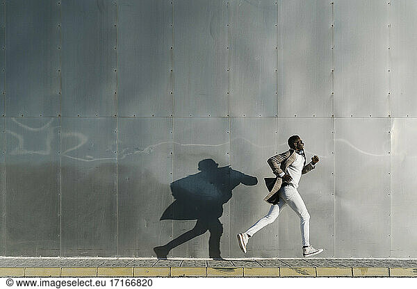 Afrikanischer Mann läuft an einer Metallwand vorbei