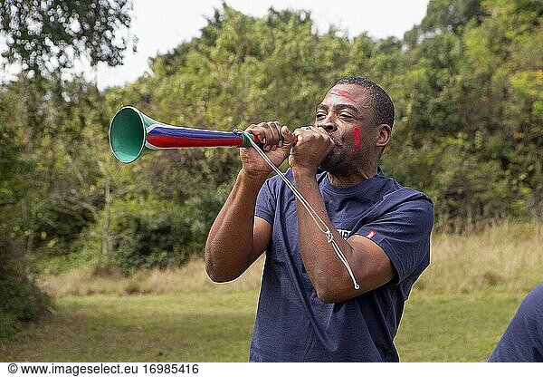 Afrikanischer Mann spielt Vuvuzela - ein traditionelles südafrikanisches Instrument