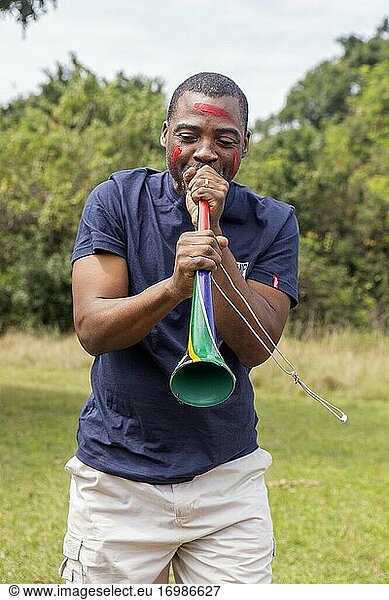 Afrikanischer Mann spielt Vuvuzela - ein traditionelles südafrikanisches Instrument