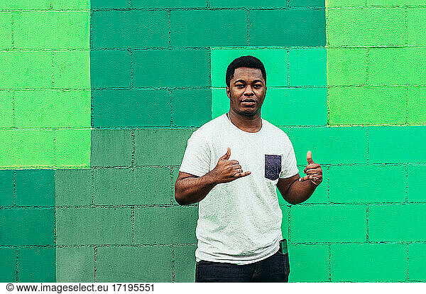 Afro American black boy on green wall background. Dressed in white t-shirt.