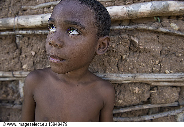 Afro-Brazilian boy looking up on a clay house background