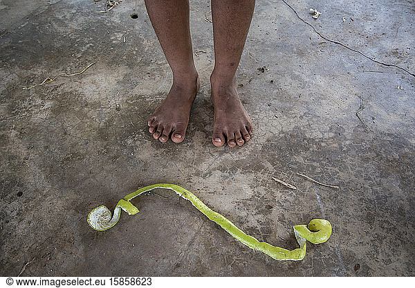 Afro-Brazilian boy`s feet and orange peel on rustic floor