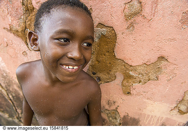 Afro-Brazilian boy with body and face with sand  smiling
