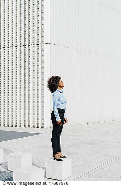 Afro businesswoman standing on concrete block