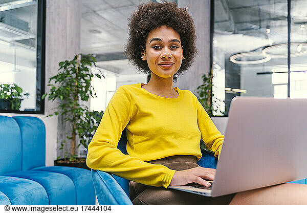 Afro businesswoman with laptop in office lobby