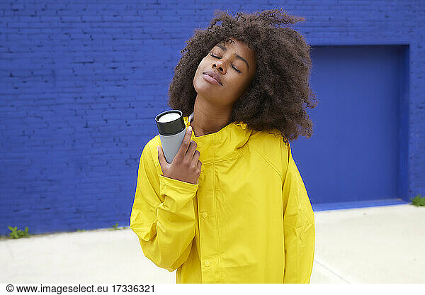 Afro-Frau mit geschlossenen Augen hält Wasserflasche