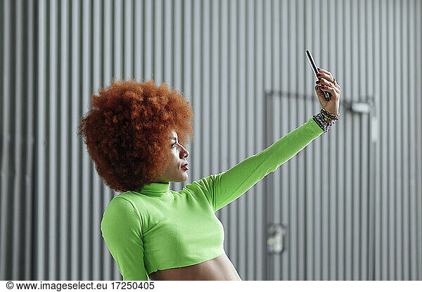 Afro-Frisur Frau nimmt Selfie von grauen Wand