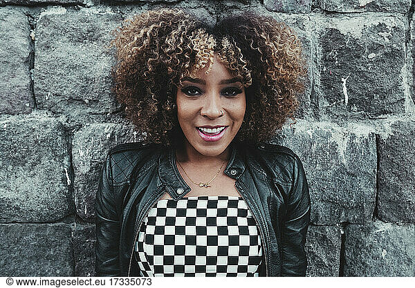 Afro hairstyle woman smiling in front of wall