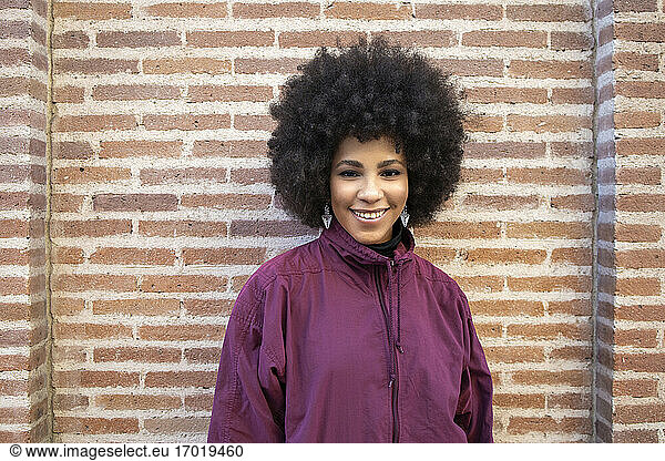 Afro junge Frau lächelnd gegen Backstein Gebäude außen