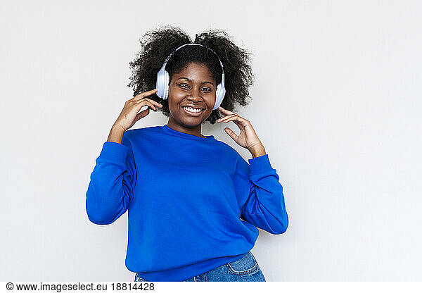 Afro woman enjoying music with wireless headphones against white background