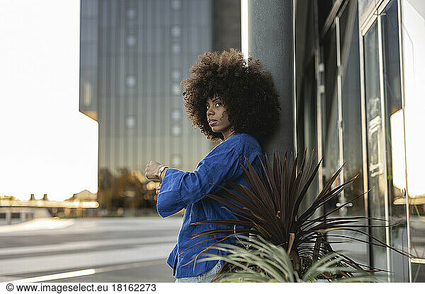 Afro woman standing by plants