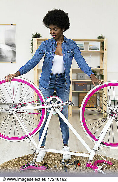 Afro woman with upside down bicycle at home