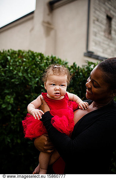 Afroamerikanische Stiefschwester hält bi-rassische Baby-Schwester