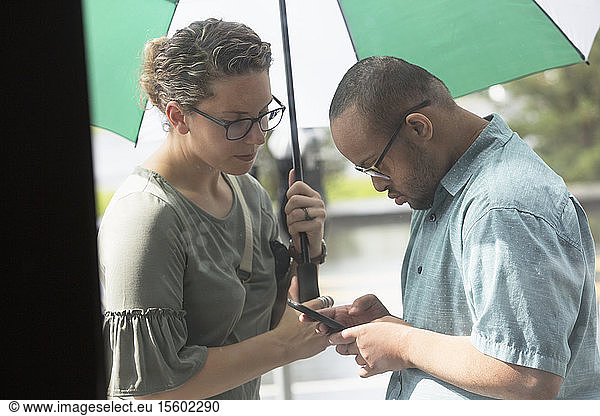 Afroamerikanischer Mann mit Down-Syndrom schaut mit seinem Freund auf sein Handy