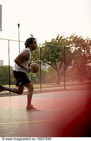 Afroamerikanischer Mann spielt Basketball im Freien