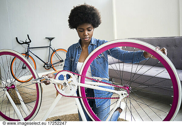 Afrofrisur Frau repariert Fahrrad zu Hause