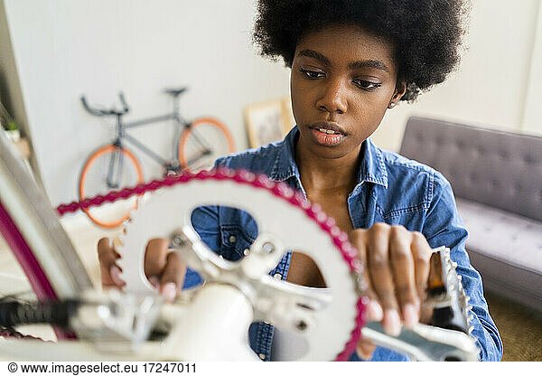 Afrofrisur Frau repariert Fahrradkette zu Hause