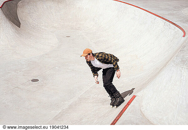 aggressive roller skater performing a trick on a railing in skatepark