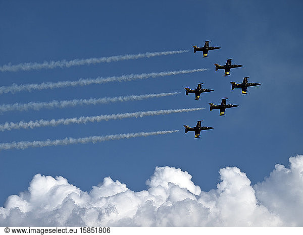 Air force fighter squadron in formation against blue sky above clouds