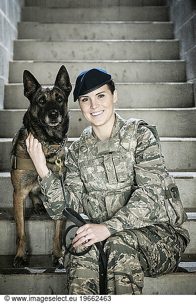 Air Force Security Forces K-9 handler  and her military working dog  sit together on a stairwell.