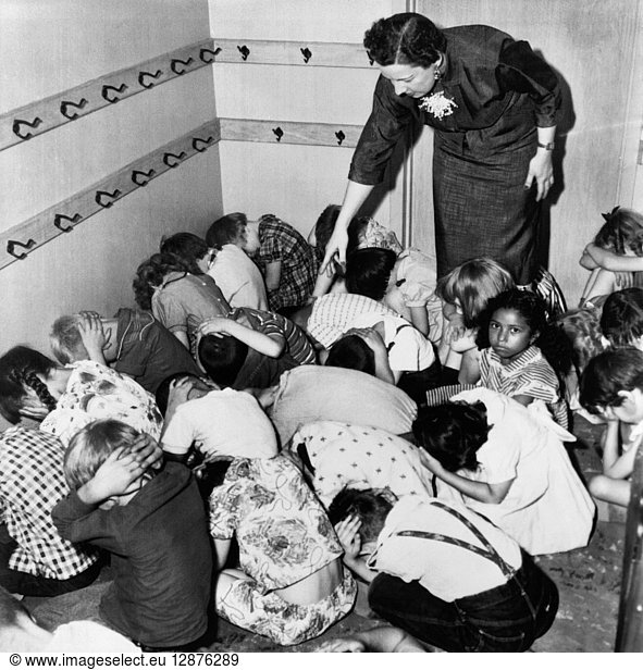 AIR RAID DRILL  1954. A kindergarten class crouches at the direction of their teacher during an air raid drill  Chicago  Illinois. Photograph  1954.