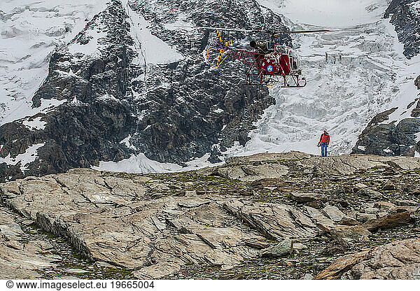 Air Zermatt rescue helicopter picking up a mountain guide to help the hotel rescue crew