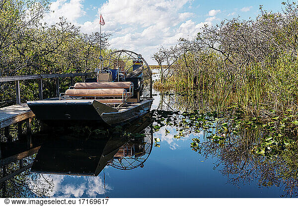 Airboat by pier in lake against sky at Everglades National Park
