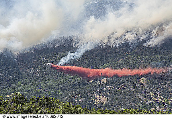 Aircraft discharging fire retardant on wildfire in forest