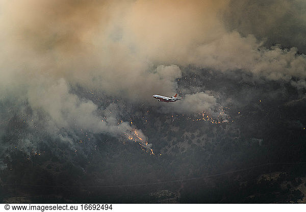 Aircraft flying over wildfire in forest