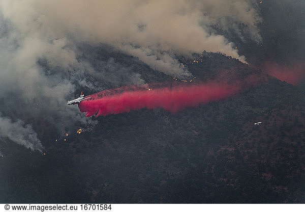 Airplane dropping fire retardant on wildfire in forest