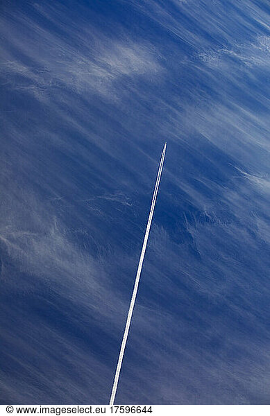Airplane leaving vapor trail against blue sky