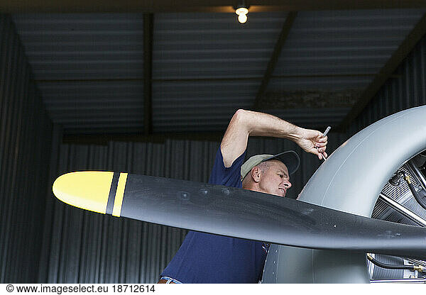 Airplane mechanic and pilot working on his World War II  SNJ-5 Navy fighter trainer.